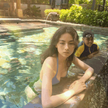 a girl in a bikini is leaning against the edge of a swimming pool