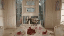 a woman in a pink dress is standing in a dining room with a table set for a dinner party .