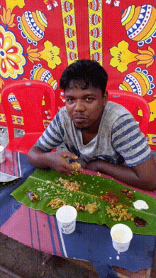 a man sits at a table with a banana leaf on it and a cup that says ' coca cola ' on it