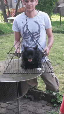 a man in a skull shirt is holding a dog on a chain