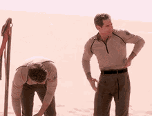 two men are standing in the sand in the desert .