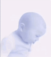 a baby is making a funny face while wearing a blue shirt .