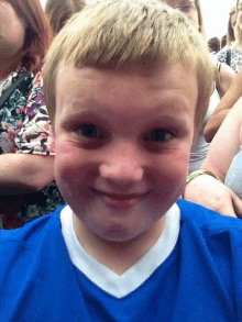 a young boy wearing a blue shirt is smiling