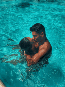 a man and a woman are kissing in a pool