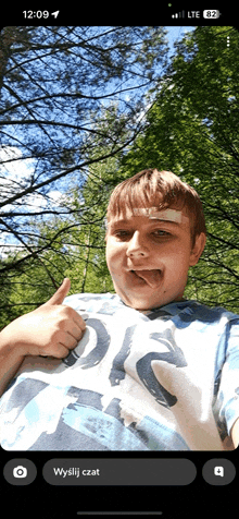 a young boy with a bandage on his forehead is giving a thumbs up