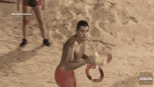 a man without a shirt is playing volleyball on a beach .