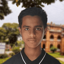 a young man in a black shirt stands in front of a blurred building