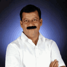 a man with a mustache wearing a white shirt stands with his arms crossed