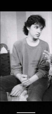 a black and white photo of a young man sitting on a couch