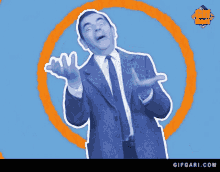 a man in a suit and tie is standing in front of an orange circle with a gifgari.com logo