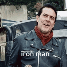 a man wearing a leather jacket and a red scarf has the word iron man on his chest