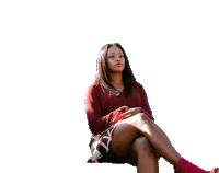 a woman in a red top and black skirt sits on a white background