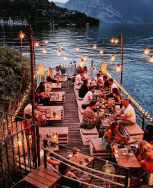 a group of people are sitting at tables near a lake