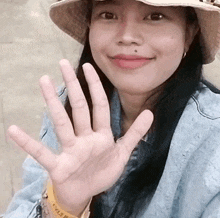 a woman wearing a hat and a watch that says levi 's on it waves her hand