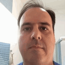 a man is taking a selfie in a bathroom with a blue shirt on .