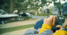 a person wearing a yellow and blue striped shirt is looking out a window with a boat in the background