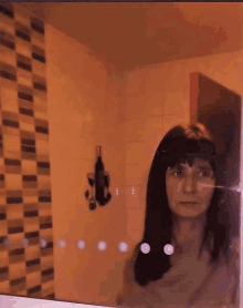 a woman is standing in front of a bathroom mirror .