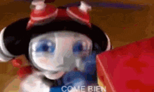 a cartoon character with a red hat and goggles is standing next to a red box that says come bien .