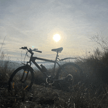 a bicycle is parked in a field with the sun shining through the clouds