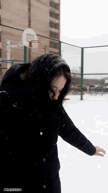 a woman is standing in the snow with a basketball hoop in the background and the word magazin on the bottom right