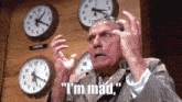 a man in a suit says " i 'm mad " in front of a wall of clocks