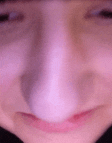 a close up of a person 's nose and mouth with a purple background .