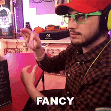 a man wearing a red hat and green glasses is sitting at a table with the word fancy above him