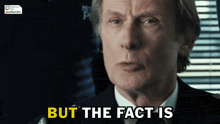 a man in a suit says but the fact is in yellow letters