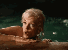 a woman is swimming in a pool with her mouth open and a surprised look on her face .