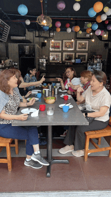 a group of women sit at a table with plates and cups