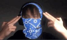 a person wearing headphones and a blue bandana covering their face