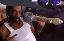 a man in a white tank top is holding a pipe that says snoop dogg