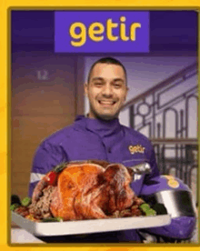 a man in a purple jacket is holding a tray of food with the word getir on it .