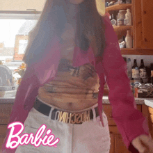 a woman is wearing a barbie belt and a pink shirt