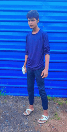 a young boy is standing in front of a blue wall .