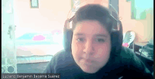 a young boy wearing headphones looks at the camera with the name luciano benjamin becerra suarez below him