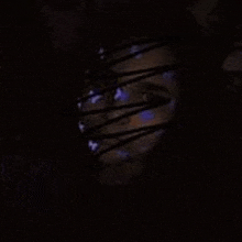 a close up of a person 's face in a dark room with a purple light coming out of it .