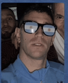 a man wearing glasses with the argentina flag reflected in the lenses