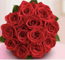 a bunch of red roses with green leaves on a table