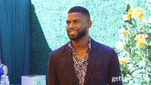 a man in a suit stands in front of a green wall and a box that says gettyimages on it