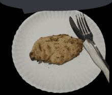 a paper plate with a piece of grilled chicken and a knife and fork on it