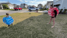 a woman in a red and pink inflatable bubble suit stands next to a boy in a blue inflatable bubble suit