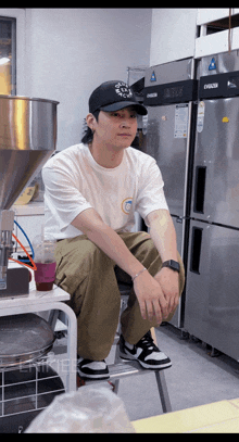 a man sits on a stool in front of a refrigerator that says emerald on it