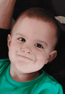 a young boy wearing a green shirt looks at the camera