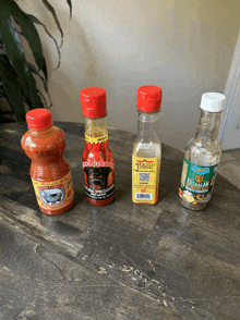four bottles of hot sauce on a table including a bottle of tabasco
