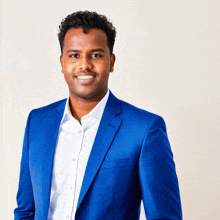 a man in a blue suit and white shirt is smiling for the camera