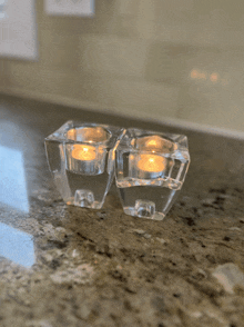 two clear glass candle holders sitting on a granite counter