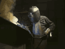 a man wearing a welding helmet is welding a piece of metal in a dark room