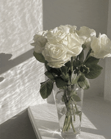 a vase filled with white roses sits on a table