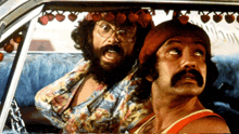a man with a beard and mustache is sitting in a car next to another man